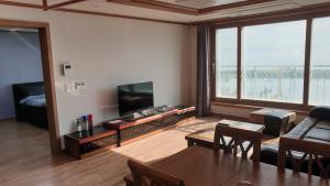 sala de estar con TV, mesa y sillas en Geoje Seaside Luxury Family Villa, en Geoje