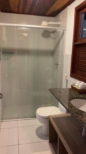 a bathroom with a toilet and a glass shower at Sol da Pipa Flats Bosque da Praia in Pipa