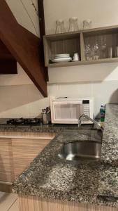 a kitchen counter with a sink and a microwave at Sol da Pipa Flats Bosque da Praia in Pipa