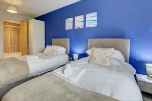 City Centre Apartment with Secure Parking by MBiZ في نورثامبتون: سريرين في غرفة نوم بحائط ازرق