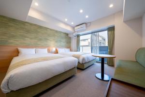 a hotel room with two beds and a table at RESI STAY Kyo Ryuvilux Nijo in Kyoto