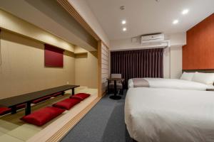 a hotel room with two beds and a desk with red pillows at RESI STAY Kyo Ryuvilux Nijo in Kyoto