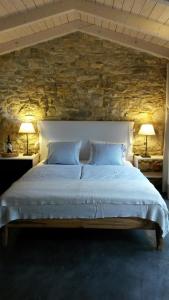 1 dormitorio con 1 cama grande y pared de piedra en Sárffy House, en Dörgicse