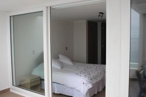 a bedroom with a white bed and a mirror at Descanso frente al mar in Viña del Mar