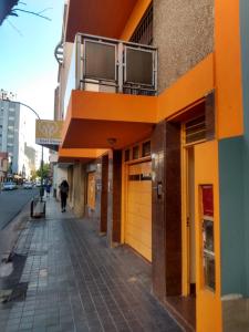 ein orangefarbenes Gebäude mit Balkon auf einem Gehweg in der Unterkunft Ser Uno in Cordoba