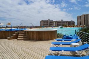 a beach with chairs and a pool with a playground at Laguna Bahía Fernanda in Algarrobo