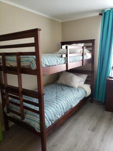 1 dormitorio con 2 literas y cortinas azules en Laguna Bahía Fernanda, en Algarrobo