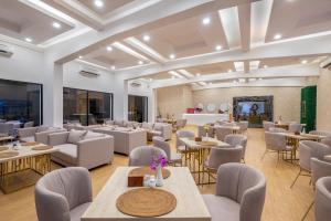 ein großes Zimmer mit Tischen und Stühlen sowie einer Lobby in der Unterkunft ABISHA Hotel Sanur in Sanur