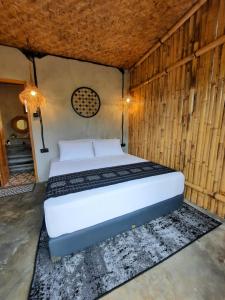 a bedroom with a white bed in a wooden wall at Sawah Ijen in Licin