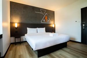 a bedroom with a large white bed with a sign on the wall at Kuda Asia Hotel Bang Saen in Bangsaen
