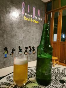 a bottle of beer sitting on a table next to a glass at สีดา​ โฮสเทล in Phetchaburi