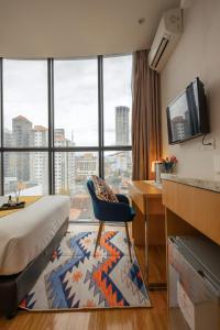 ジョージタウンにあるSummer Tree Hotel Penangのベッド、デスク、窓が備わるホテルルームです。
