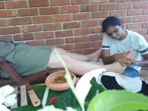 a man sitting next to a brick wall at Eco Breeze - Unawatuna in Galle