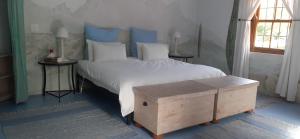 a bedroom with a large white bed with a wooden trunk at Gecko Cottage at Artemis in Franschhoek