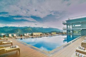 a large swimming pool with chairs and a building at Vibe Munnar in Munnar