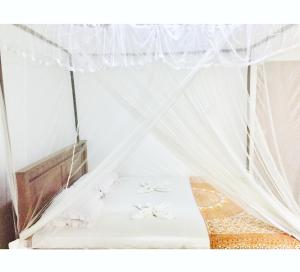 a bed in a room with white mosquito nets at Surfing Waves Madiha in Matara