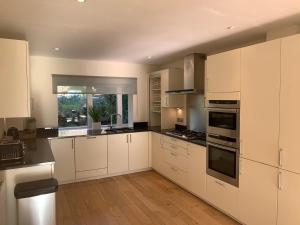 a large kitchen with white cabinets and a window at Harrier Lodge in Cirencester