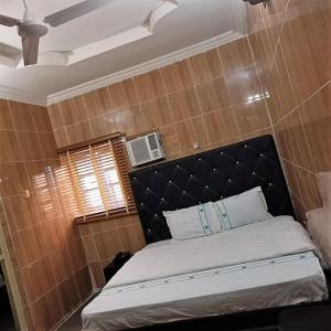 1 dormitorio con 1 cama con cabecero negro y ventana en Elites Lodge en Port Harcourt