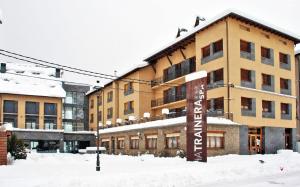 un grand bâtiment avec de la neige devant lui dans l'établissement Apartaments Trainera, à Esterri d'Àneu