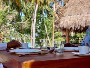 einem Holztisch mit Tassen, Tellern und Gläsern in der Unterkunft Island Luxury Boutique Hotel - Fulhadhoo in Fulhadhoo