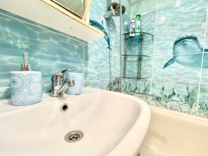 a white sink in a bathroom with blue tiles at 1-комнатная Квартира Взлётная 51 in Barnaul