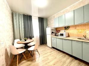 a kitchen with a table and chairs and a refrigerator at 1-комнатная Квартира Взлётная 51 in Barnaul