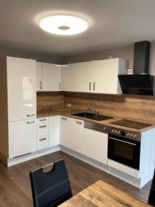 a kitchen with white cabinets and a sink and a stove at Ferienwohnung Am Schlosspark Ettersburg bei Weimar in Ettersburg