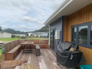 a wooden deck with a table and a bench at Hosts on the Coast Admirals Gold in Cooks Beach