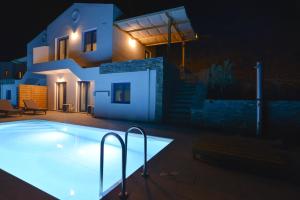 a swimming pool in front of a house at night at Kea live in Blue Villa with Pool - Cyclades in Melissaki