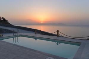 a swimming pool with a sunset in the background at Kea live in Blue Villa with Pool - Cyclades in Melissaki