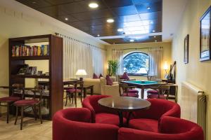 a waiting room with red chairs and tables at Hotel Valle De Izas in Sallent de Gállego