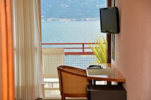 a room with a desk with a television and a window at Hotel Lido in Limone sul Garda