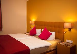 um quarto de hotel com uma cama com almofadas vermelhas e brancas em Landgasthof Schneider, Westfeld em Schmallenberg