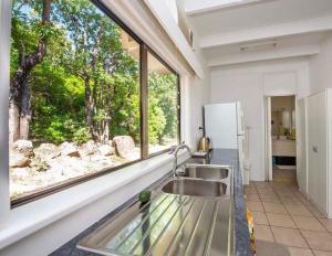 a kitchen with a sink and a large window at Nature Retreat on Mandalay in Nelly Bay