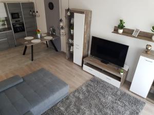 uma sala de estar com uma televisão de ecrã plano e uma mesa em Sunset Apartman em Siófok