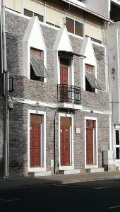 - un bâtiment en briques avec des portes rouges et un balcon dans l'établissement Casa Privada do Plateau, à Praia
