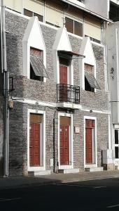 a brick building with red doors and a balcony at Casa Privada do Plateau in Praia