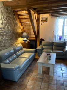 a living room with a leather couch and a table at Theuville maison les Bornes in Theuville