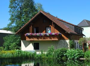 ein Haus mit einem Balkon mit Blumen darauf in der Unterkunft Landpension Heidi Machold in Weißenstadt