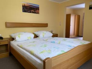 ein Schlafzimmer mit einem großen Bett mit weißer Bettwäsche in der Unterkunft Landpension Heidi Machold in Weißenstadt