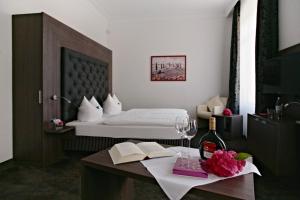 a bedroom with a bed and a table with a bottle of wine at Badhotel Bad Brückenau in Staatsbad Brückenau