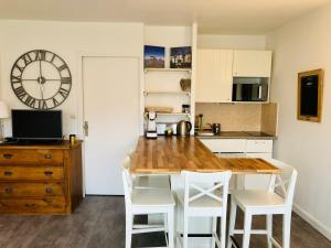 una cucina con tavolo, sedie e orologio di Bel appartement bord de mer 4 pers Arcachon centre ad Arcachon