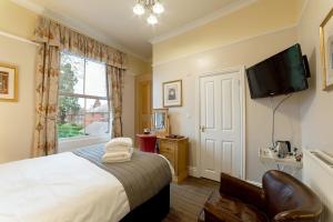 a bedroom with a bed and a television at Charades Guest House in Hereford