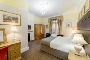 a bedroom with a bed and a desk and two lamps at Charades Guest House in Hereford