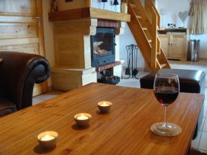 a glass of wine on a wooden table with a fireplace at Chalet Clementine in Oz