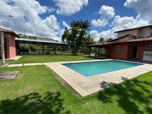 a swimming pool in a yard next to a house at Sitio Barth in Porto Seguro