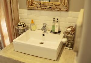 Un lavabo blanco en un baño con espejo. en The Villa Salt Rock, en Ballito 28 fotos más