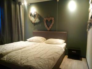 a bedroom with a bed with two hearts on the wall at Het Dobbertje, charmant houten huisje in Sint Maartensvlotbrug +37 photos