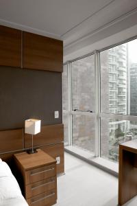 a bedroom with a bed and a large window at Duplex Suite NYC Berrini 511 in Sao Paulo