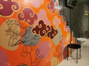 an orange wall with a painting on it at สีดา​ โฮสเทล in Phetchaburi